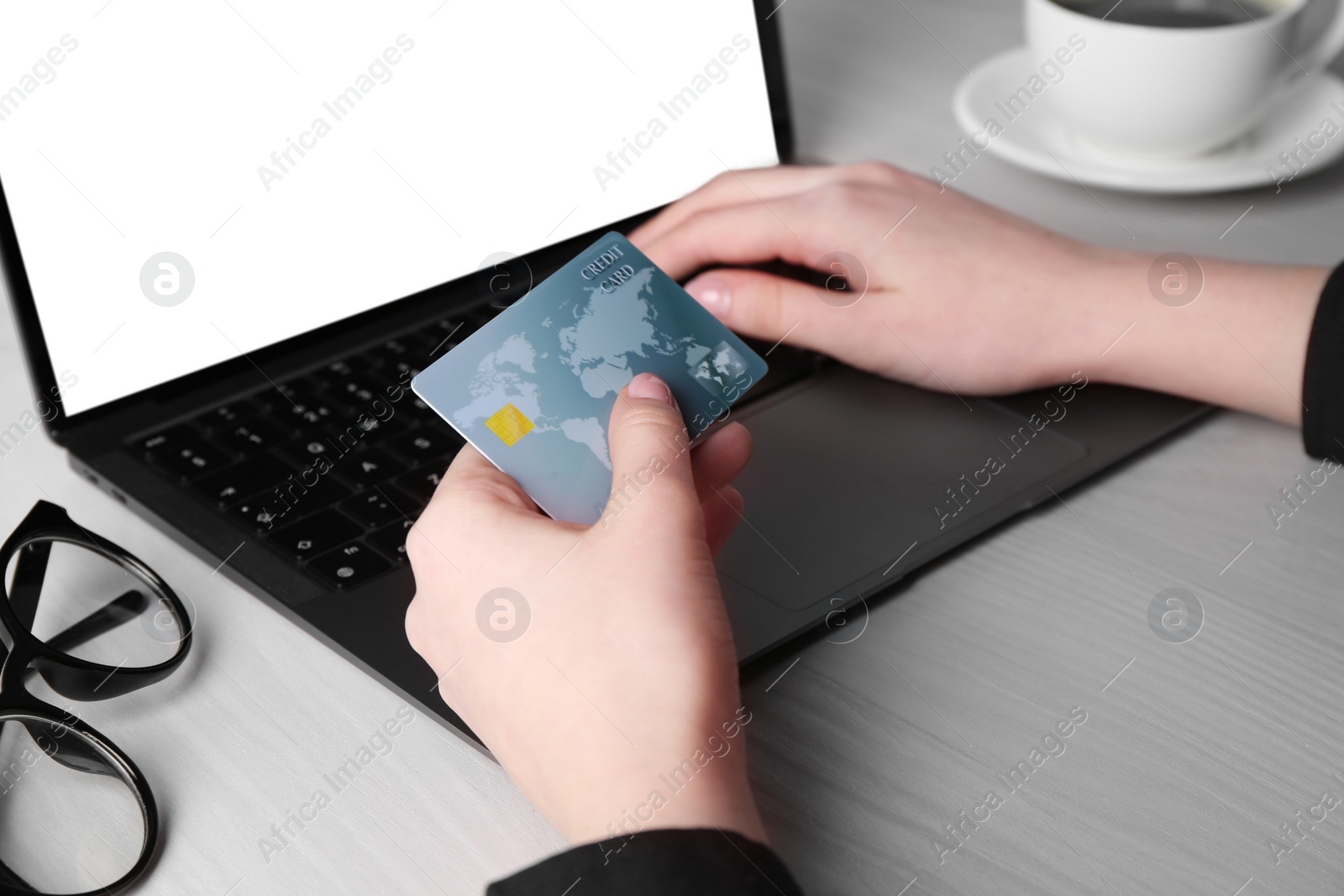 Photo of Online payment. Woman with laptop and credit card at white wooden table, closeup