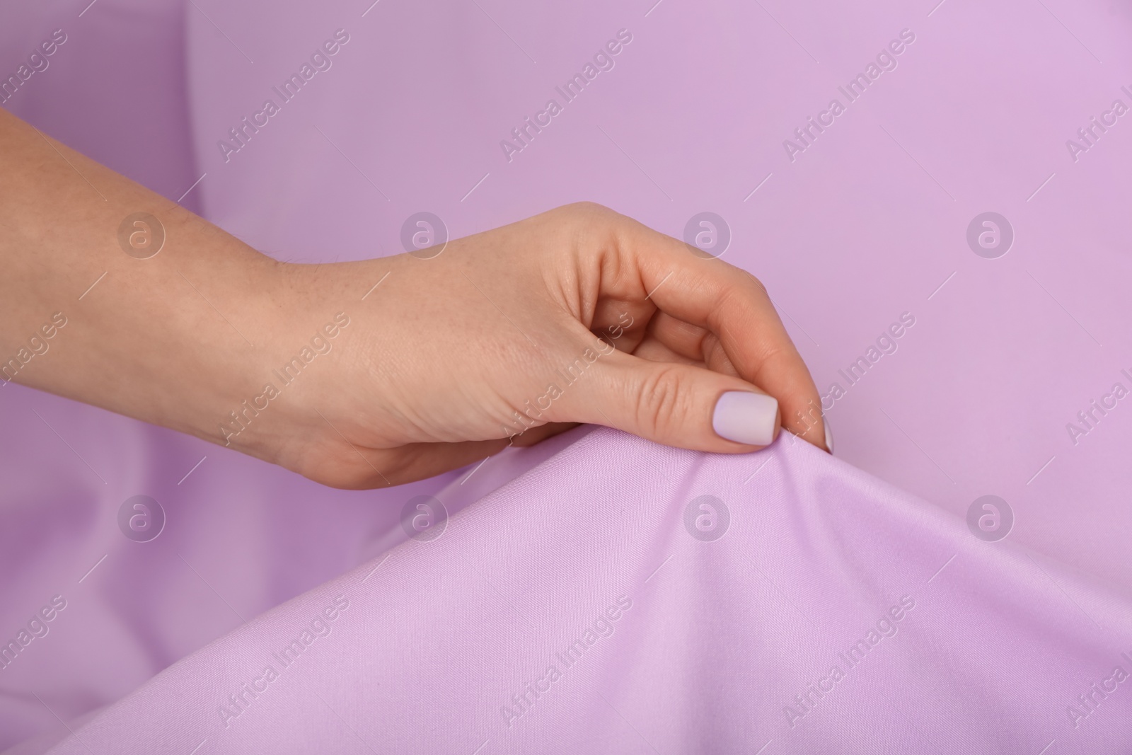 Photo of Woman touching soft violet fabric, closeup of hand