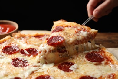 Photo of Woman taking slice of tasty pepperoni pizza at table, closeup