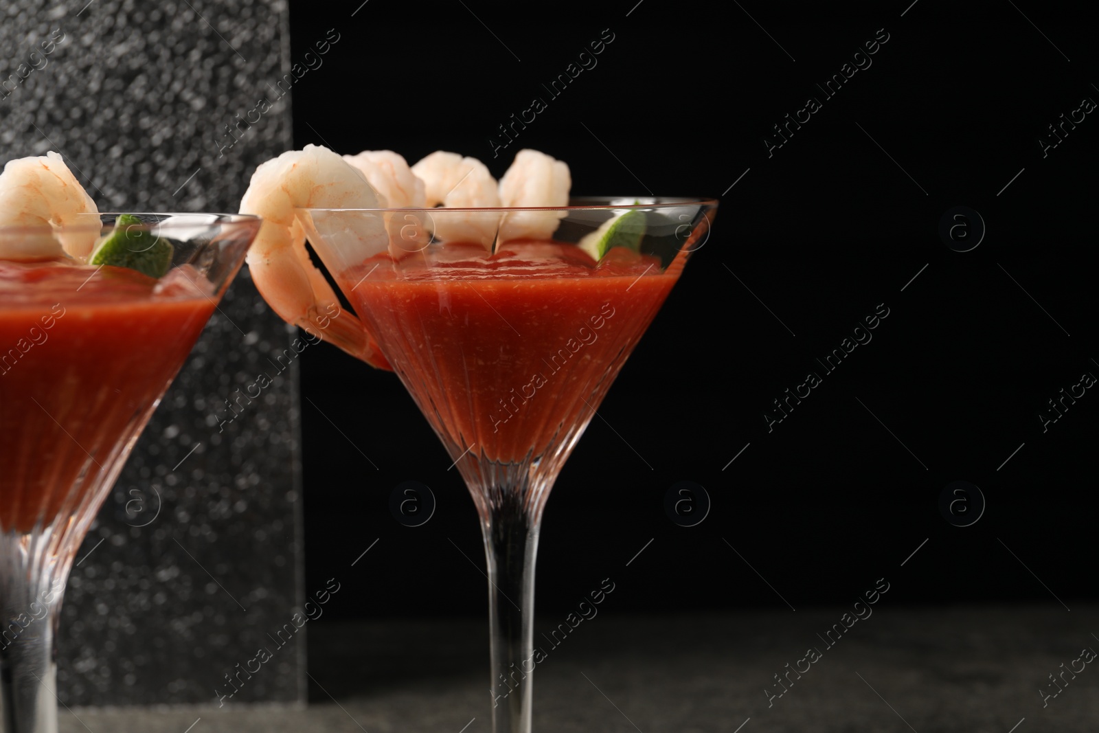 Photo of Tasty shrimp cocktail with sauce and lime in glasses on grey table, space for text