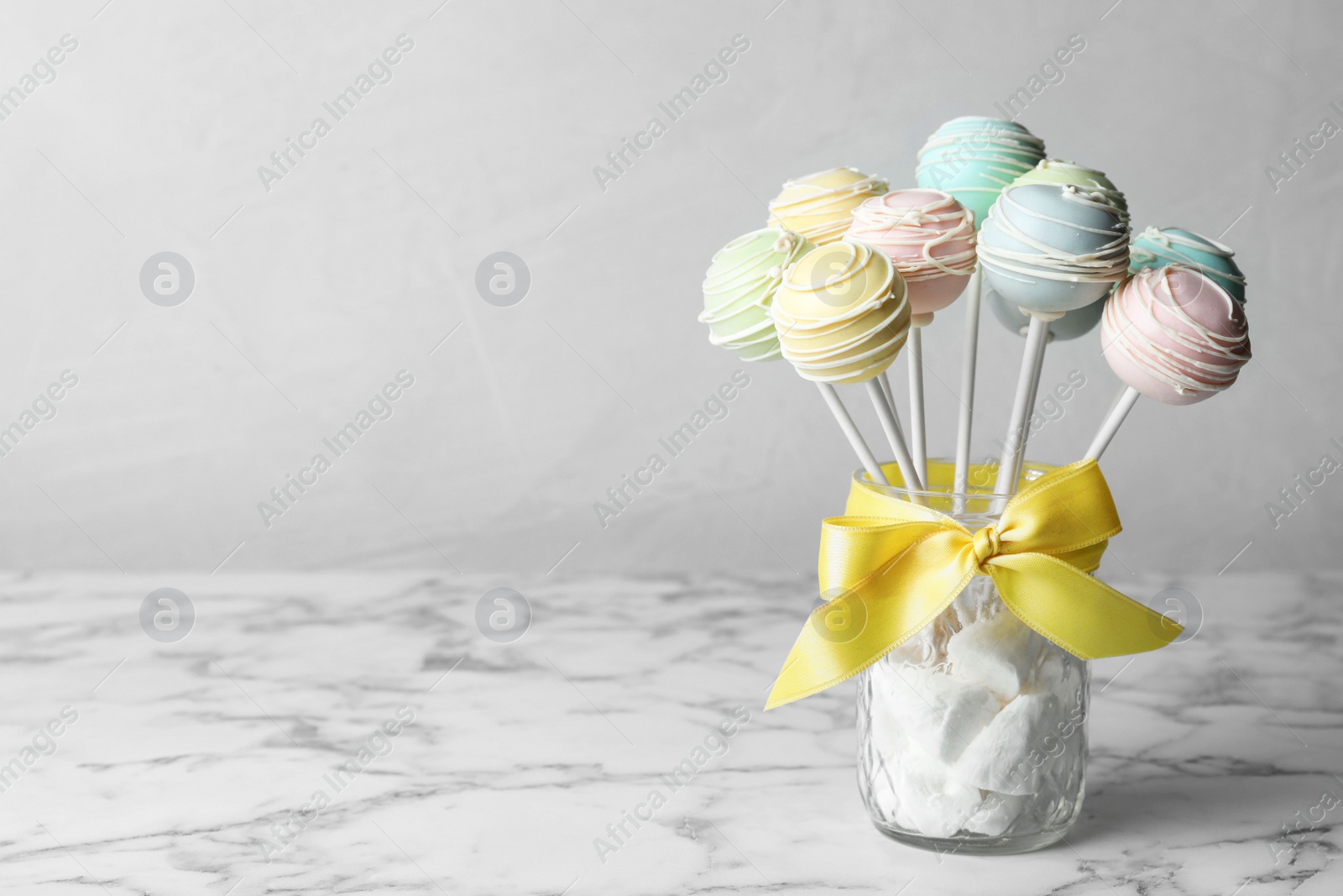 Photo of Sweet cake pops on white marble table against grey background. Space for text