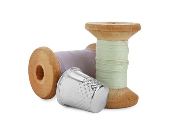 Thimble and spools of sewing threads isolated on white