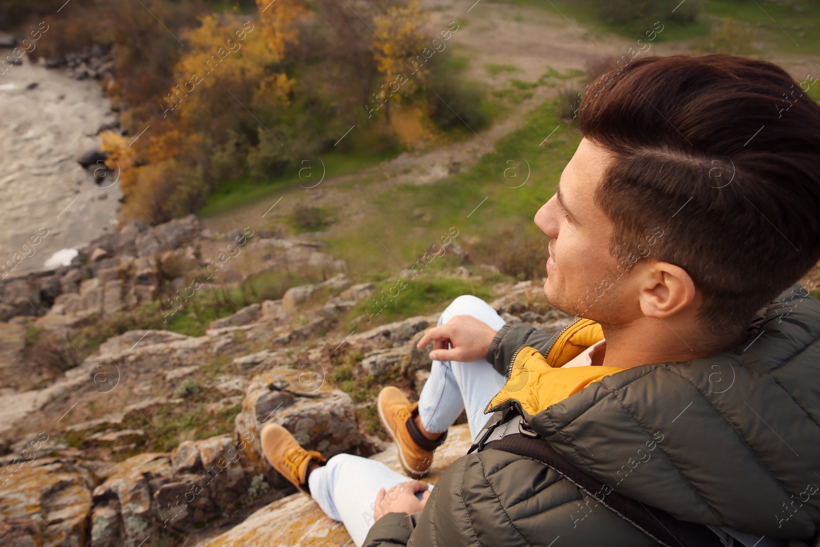 Photo of Hiker sitting on steep cliff and enjoying beautiful view