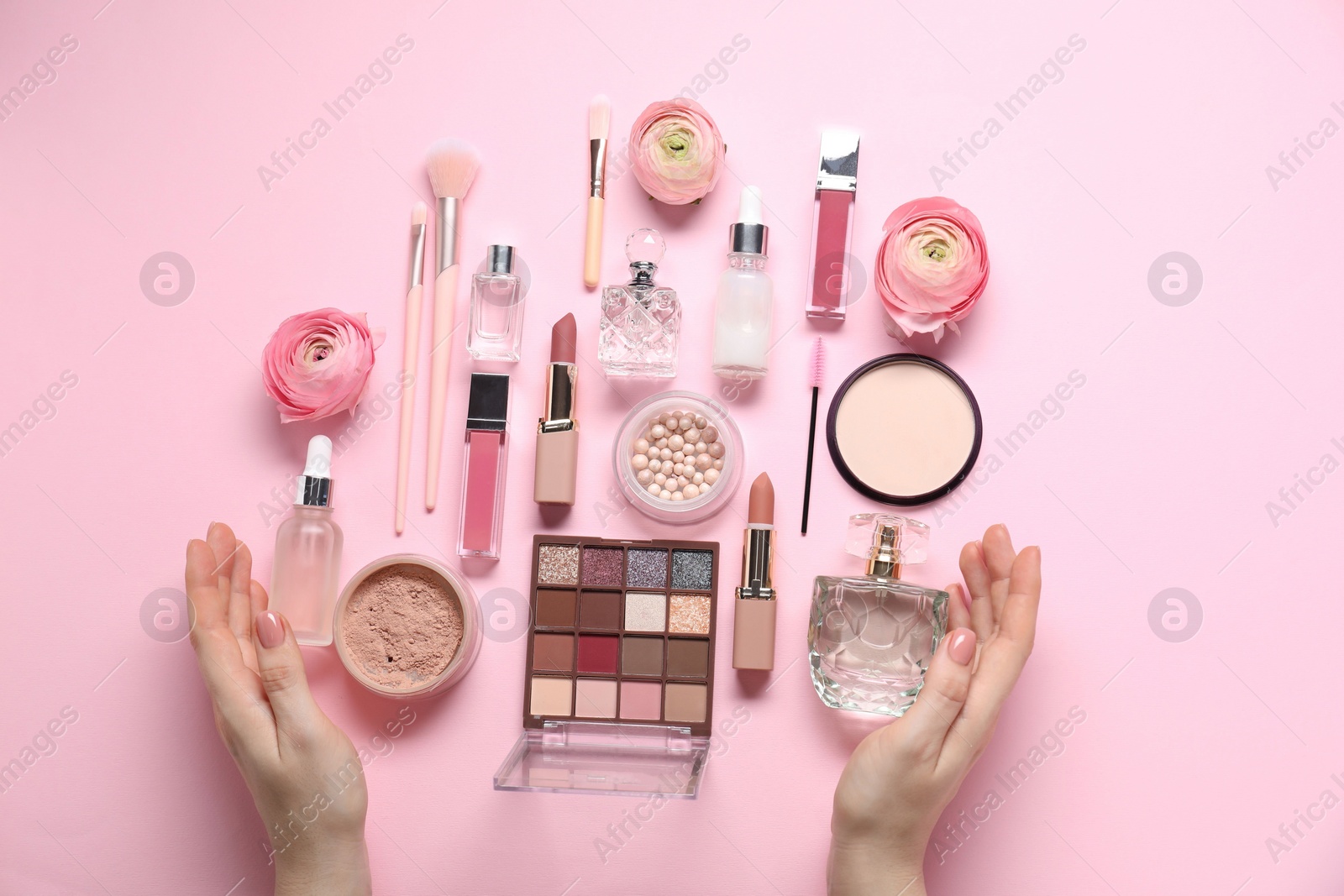 Photo of Woman with different makeup products and beautiful spring flowers on pink background, top view