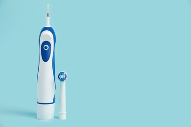 Photo of Electric toothbrush on light blue background, space for text