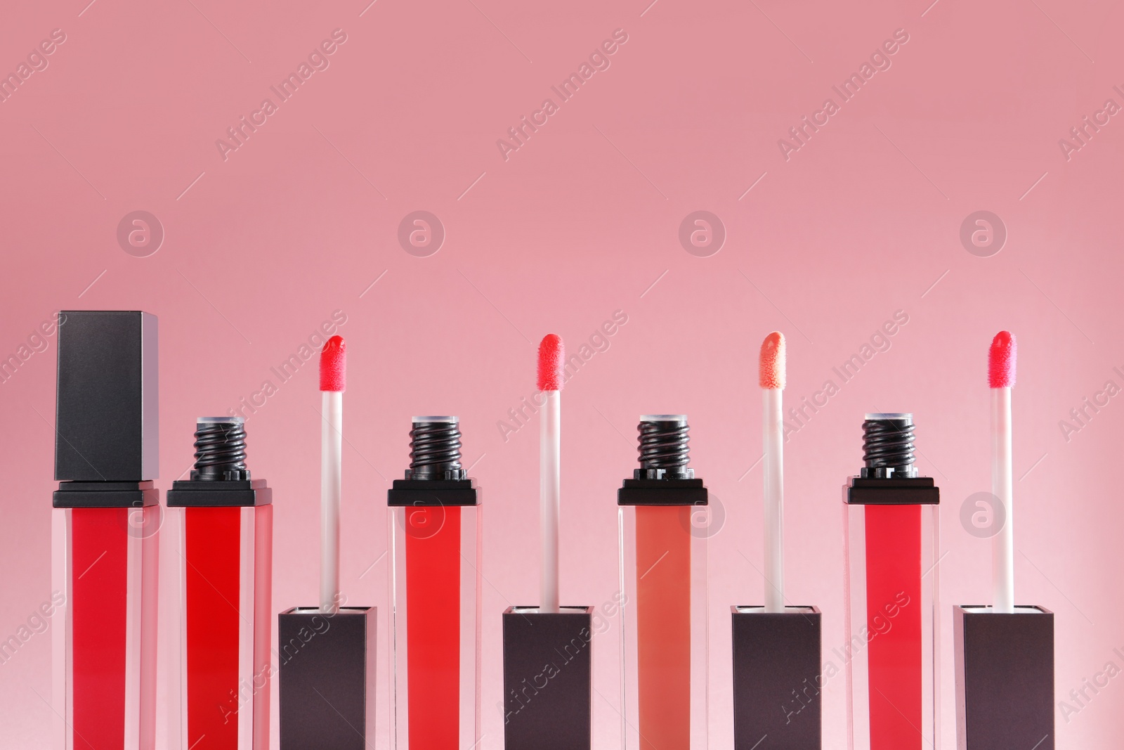Photo of Liquid lipsticks with applicators on color background