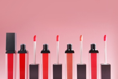 Photo of Liquid lipsticks with applicators on color background