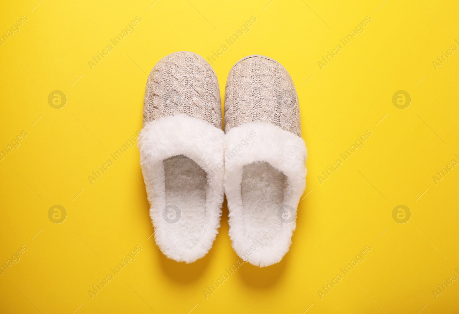 Photo of Pair of beautiful soft slippers on yellow background, top view