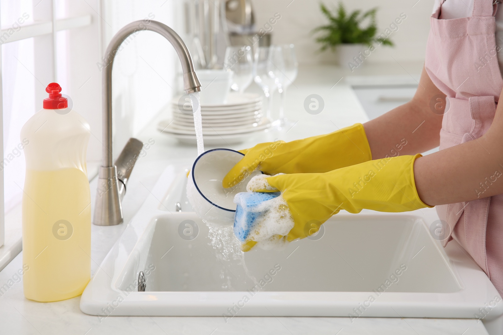 Photo of Woman washing bowl in modern kitchen, closeup