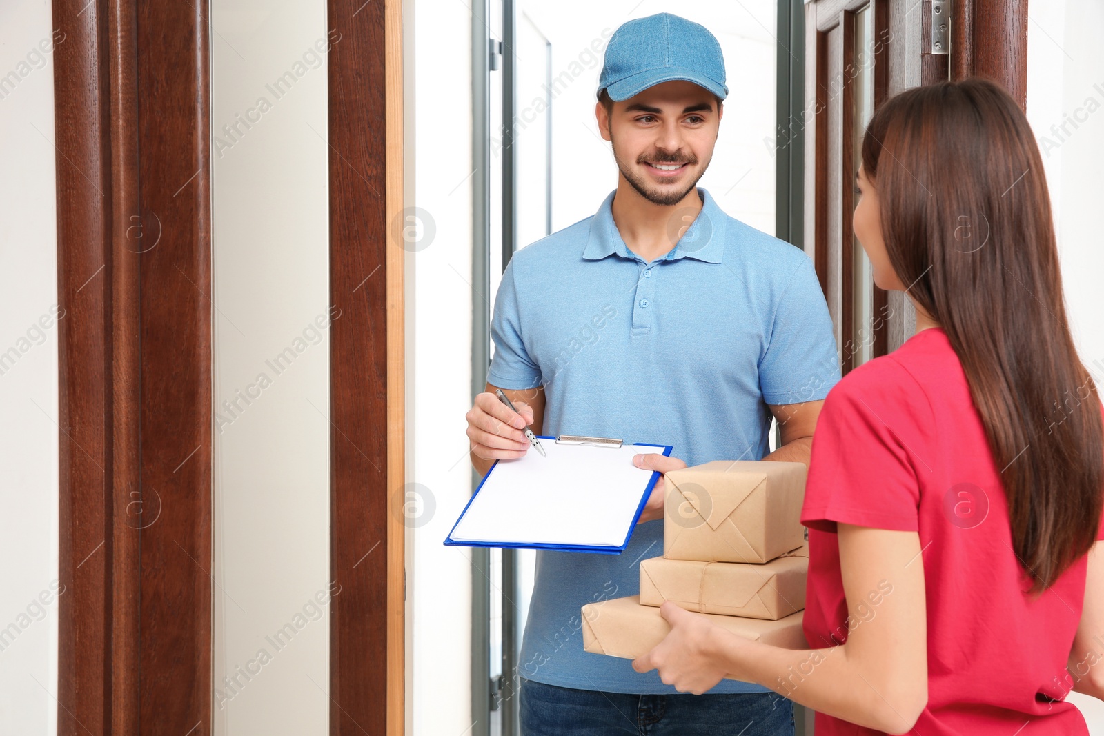 Photo of Woman receiving parcels from delivery service courier indoors