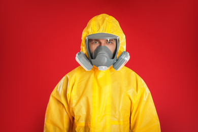 Photo of Man wearing chemical protective suit on red background. Prevention of virus spread