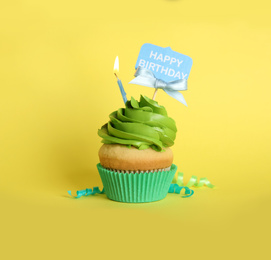 Beautiful birthday cupcake and streamers on yellow background