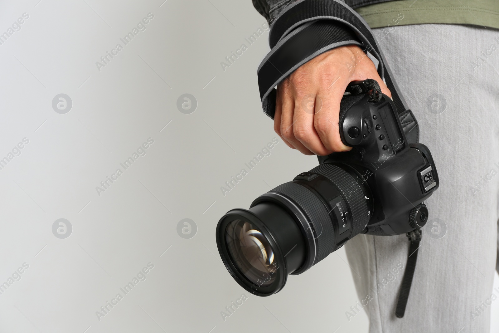 Photo of Professional photographer with modern camera on light background in studio, closeup