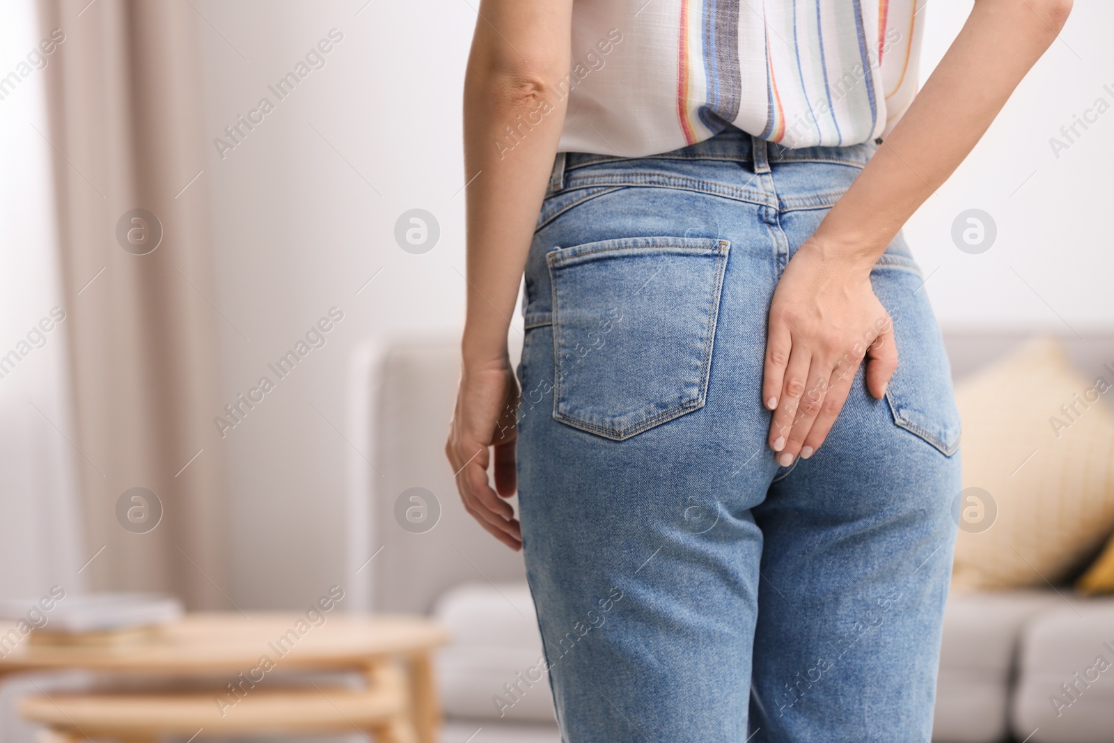 Photo of Young woman suffering from hemorrhoid at home, closeup