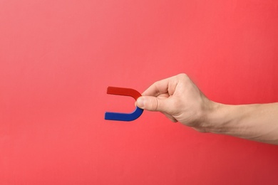 Man holding magnet on color background, closeup. Space for text