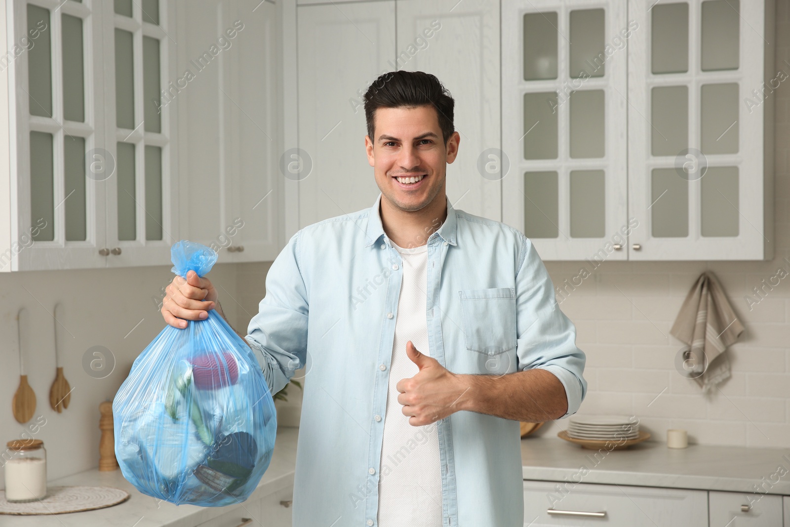 Photo of Man holding full garbage bag at home