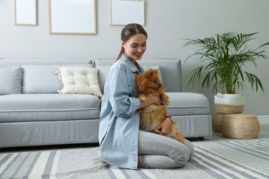 Photo of Happy young woman with cute dog in living room