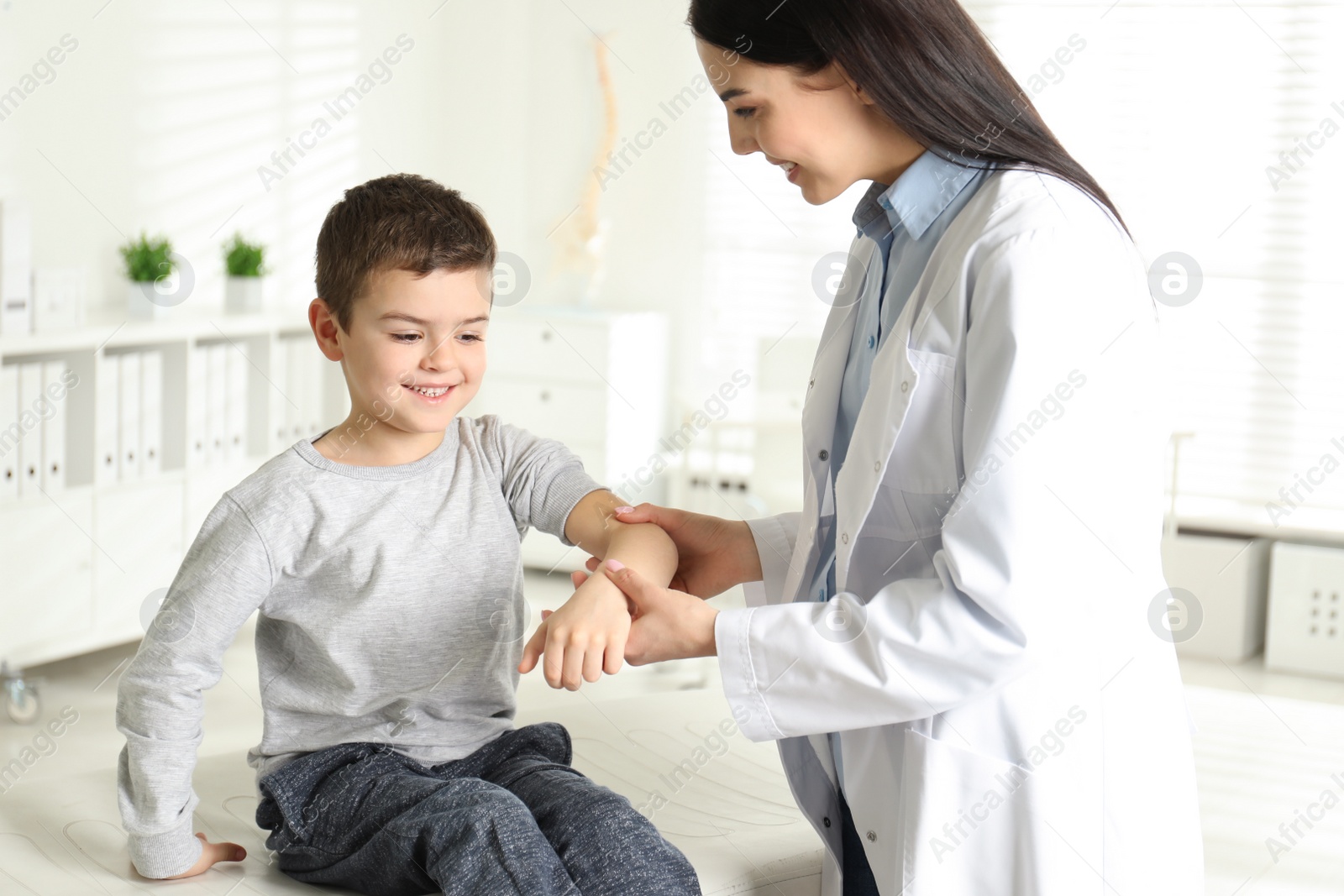 Photo of Professional orthopedist examining little patient's arm  in clinic