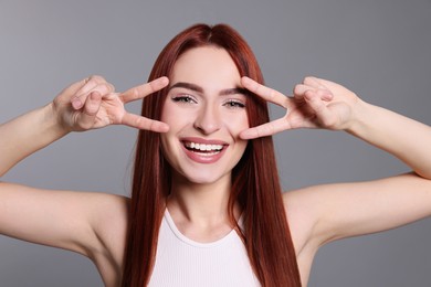 Photo of Happy woman with red dyed hair having fun on light gray background