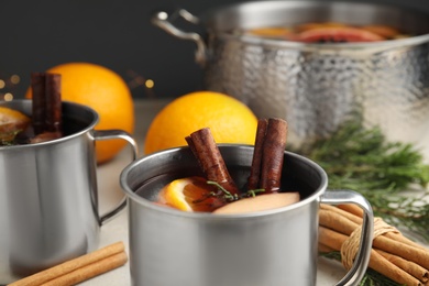 Tasty mulled wine with spices in mug on table