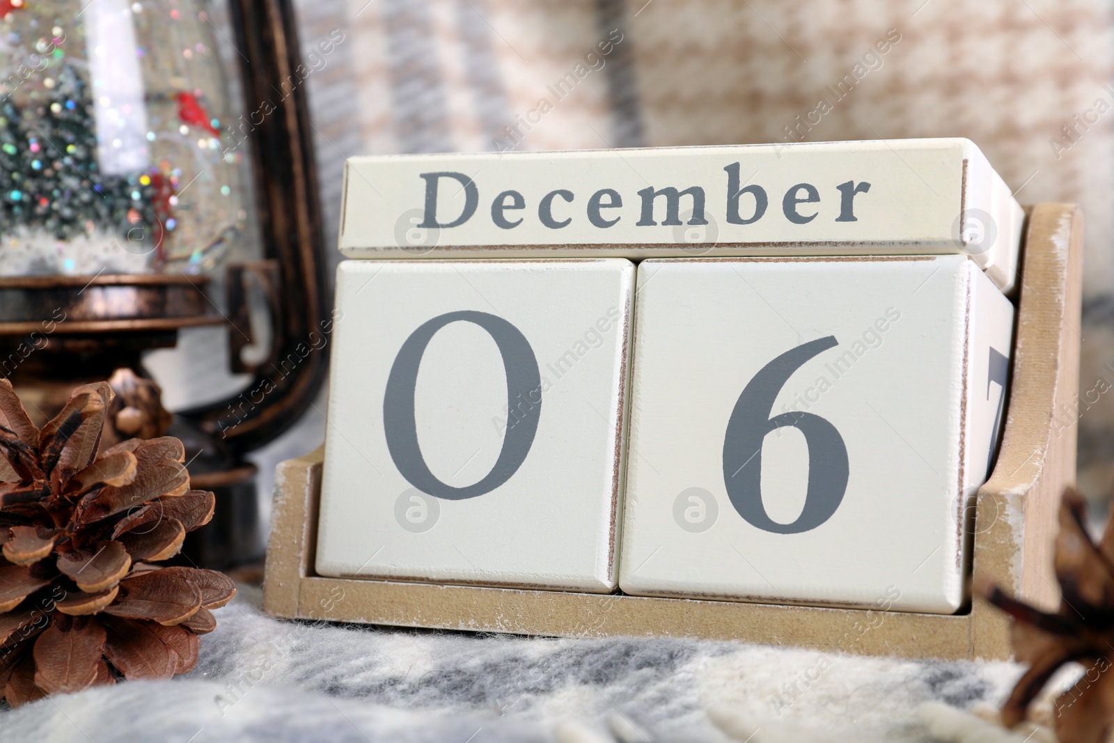 Photo of Saint Nicholas Day. Block calendar with date December 06 and festive decor on plaid, closeup