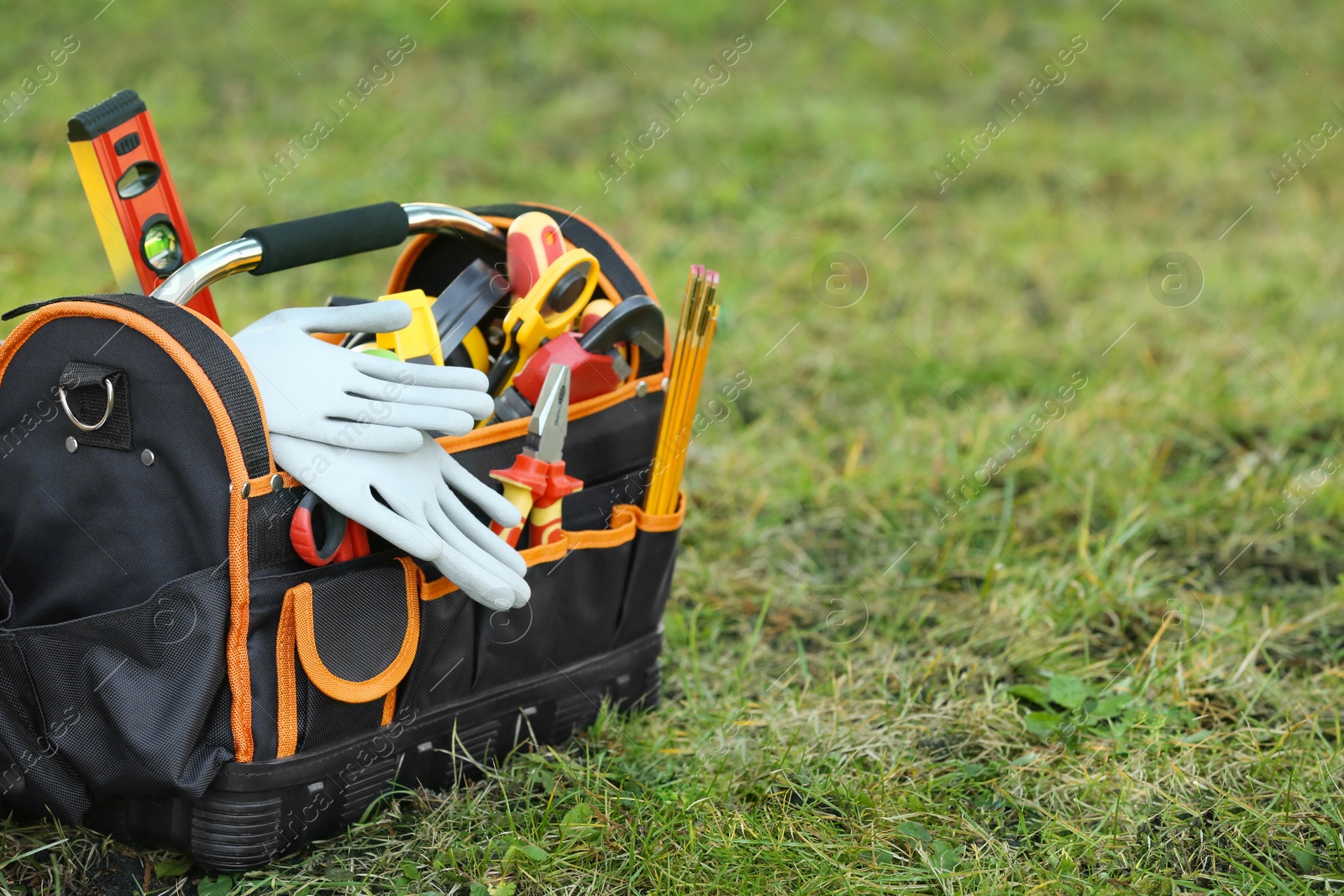 Photo of Bag with different tools for repair on grass outdoors, space for text