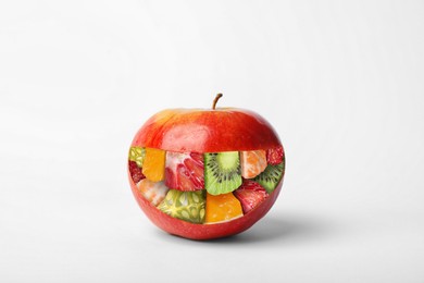 GMO concept. Fresh ripe apple and pieces of different fruits inside of it