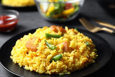 Photo of Delicious rice pilaf with meat on black plate, closeup