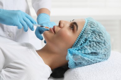 Photo of Doctor giving lips injection to young woman in clinic. Cosmetic surgery