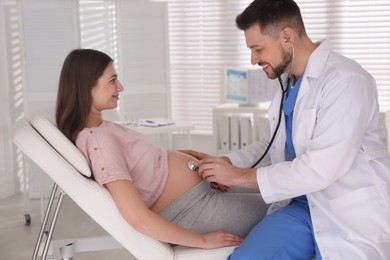 Photo of Doctor examining pregnant woman with stethoscope in clinic