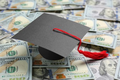 Photo of Scholarship concept. Graduation cap on banknotes, closeup