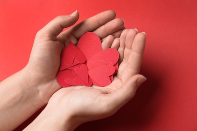 Photo of Woman holding paper hearts on red background, closeup. Happy Valentine's Day