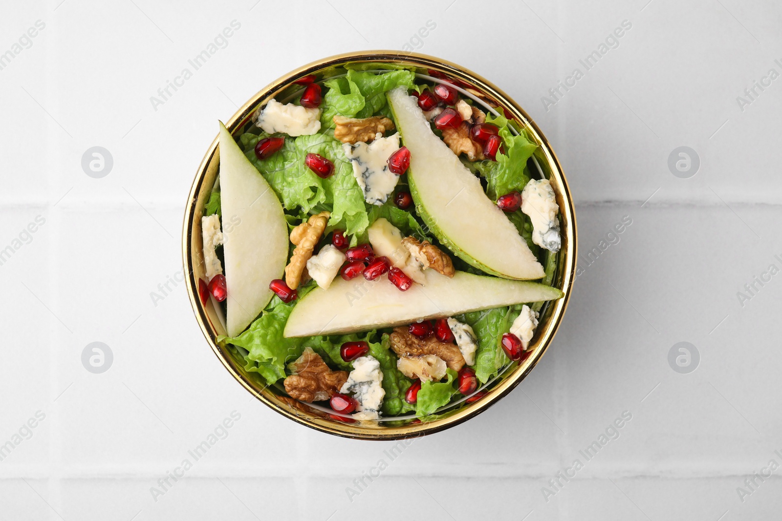 Photo of Delicious pear salad in bowl on light tiled table, top view