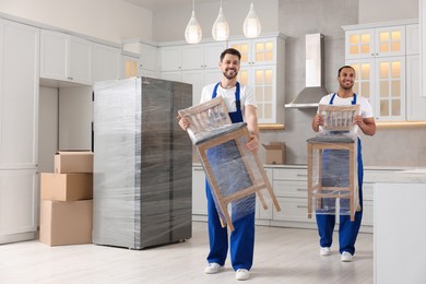 Male movers carrying chairs in new house