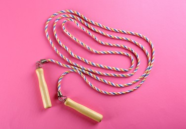 Photo of Skipping  rope on pink background, top view. Sports equipment
