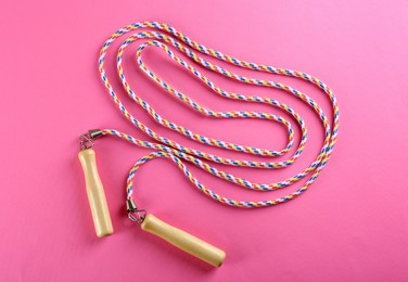 Skipping  rope on pink background, top view. Sports equipment