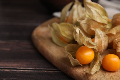 Ripe physalis fruits with calyxes on wooden table, closeup. Space for text