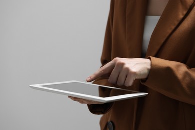 Photo of Closeup view of woman using modern tablet on grey background