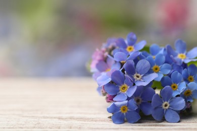 Photo of Beautiful blue Forget-me-not flowers on white wooden table, closeup. Space for text