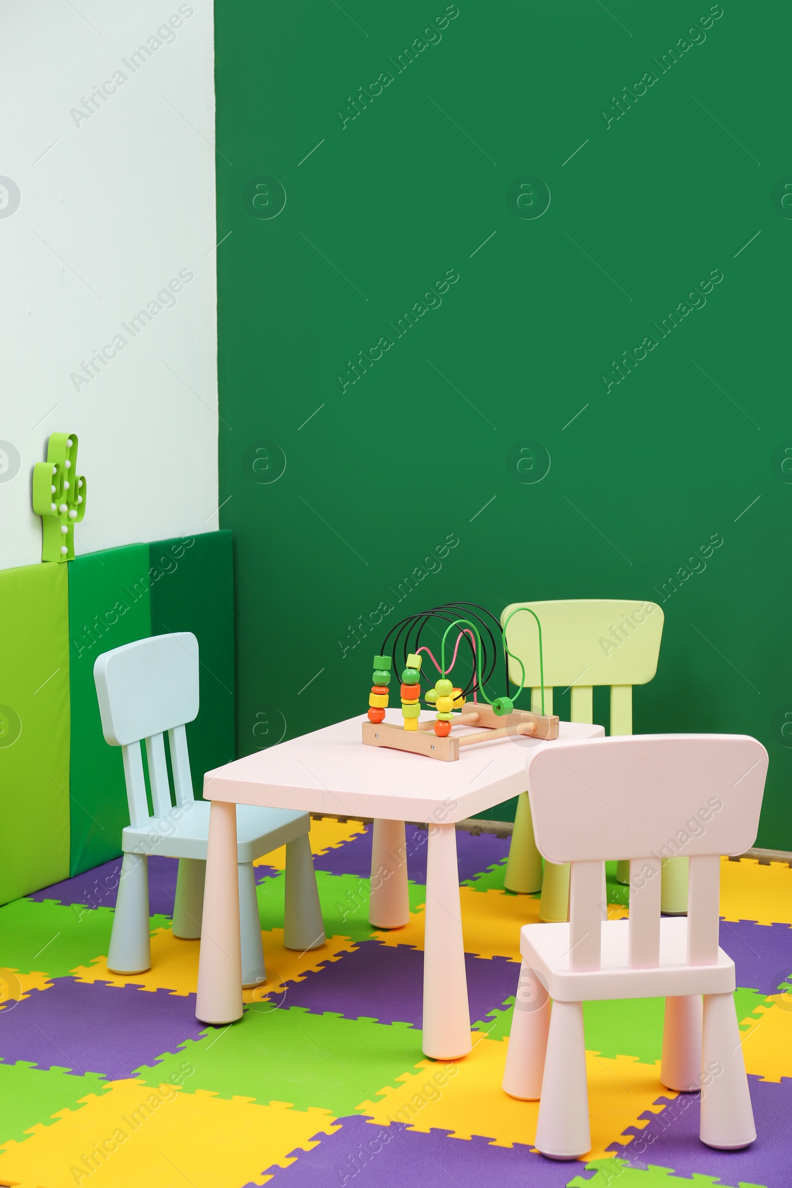 Photo of Stylish playroom interior with table and chairs. Space for text