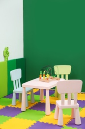 Photo of Stylish playroom interior with table and chairs. Space for text