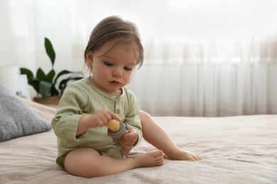 Photo of Cute baby girl with nibbler on bed at home. Space for text