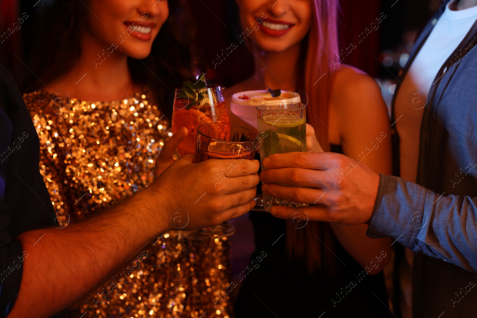 Photo of Friends clinking glasses with fresh cocktails in bar, closeup