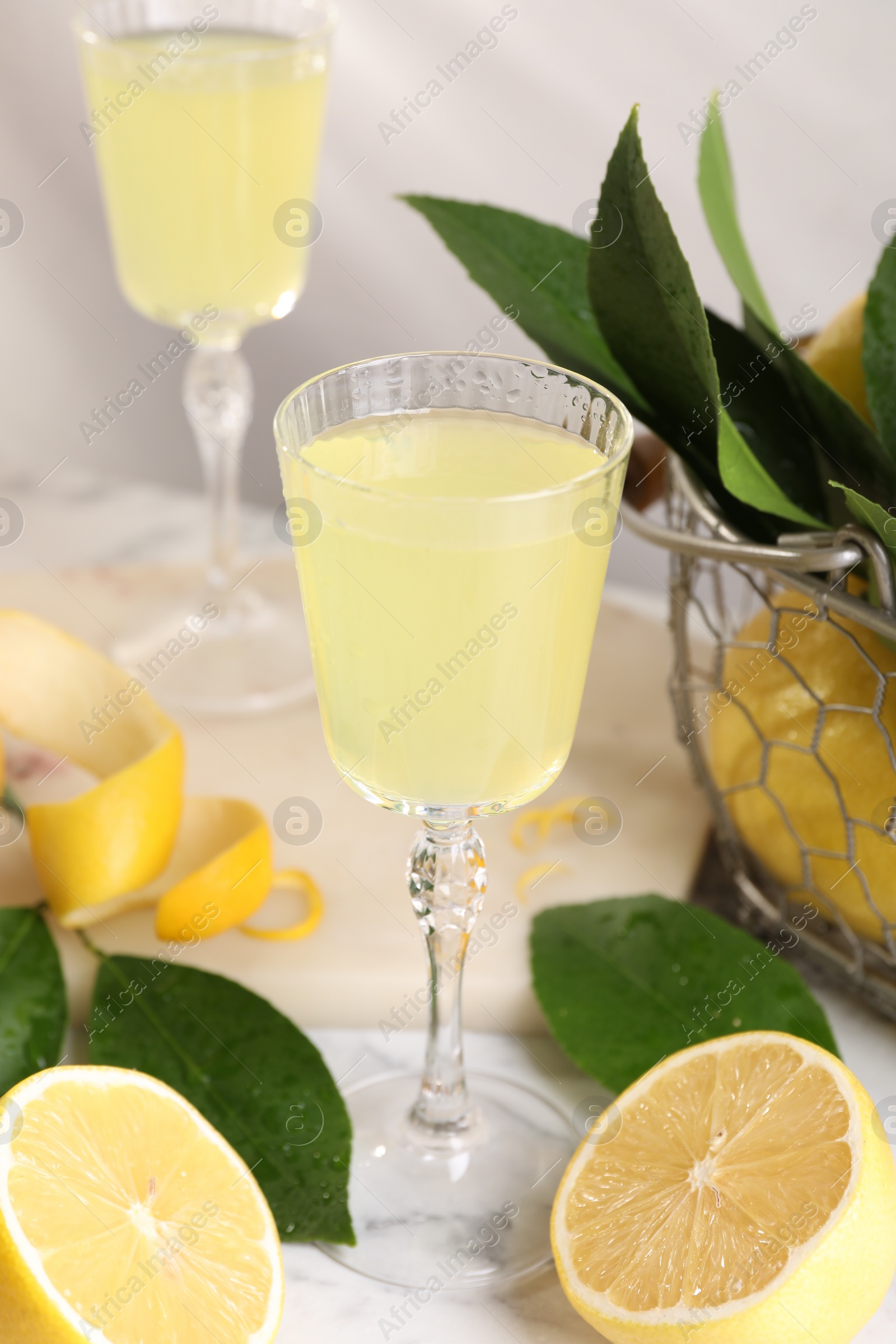 Photo of Tasty limoncello liqueur, lemons and green leaves on table
