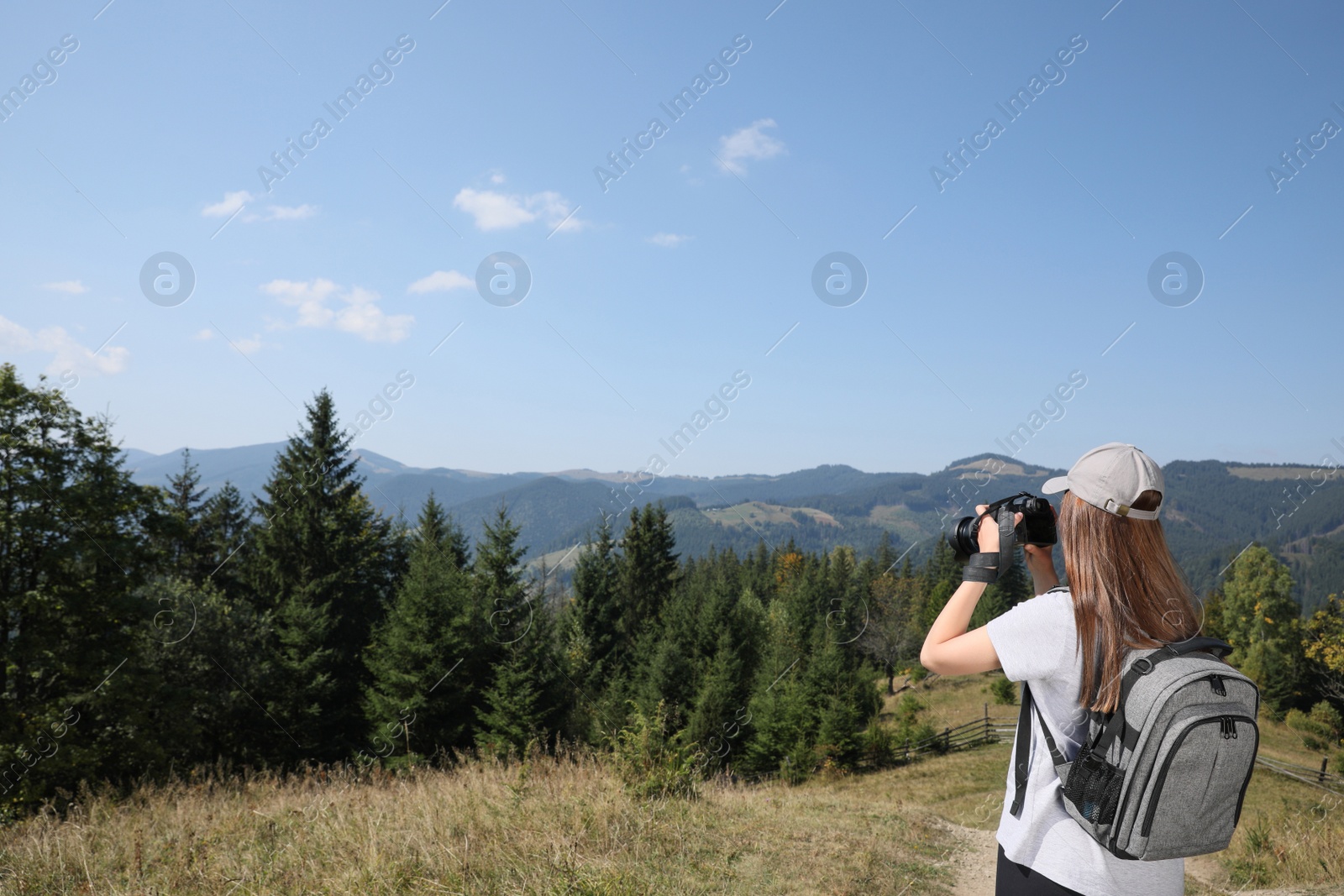 Photo of Professional photographer taking picture with modern camera in mountains. Space for text