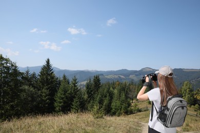 Professional photographer taking picture with modern camera in mountains. Space for text