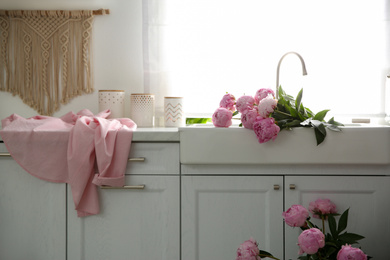 Beautiful pink peonies in stylish kitchen interior