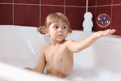 Photo of Little girl bathing in tub at home