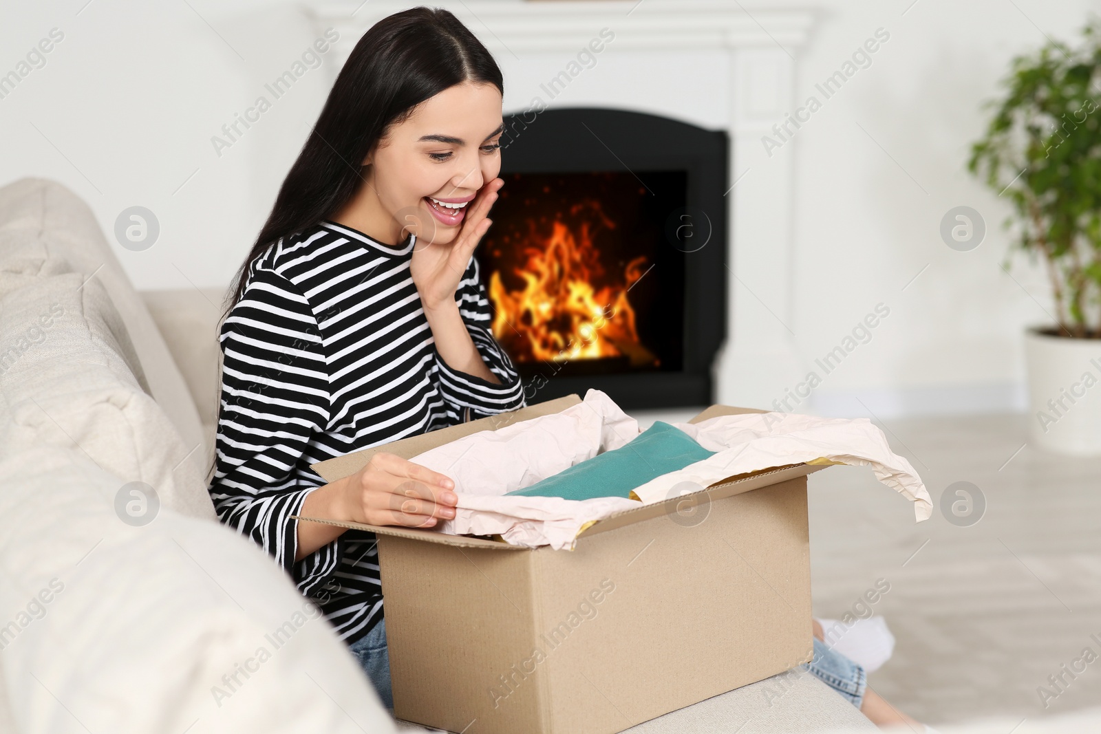 Photo of Emotional young woman with parcel at home. Internet shopping