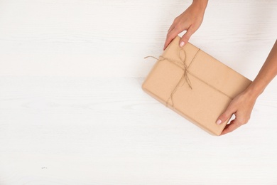 Photo of Woman holding parcel and space for text on wooden background, top view